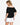 Model wearing white off-shoulder airflow dot top with puff sleeves and bow details, styled for a romantic, airy look, studio background