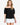 Model wearing white off-shoulder airflow dot top with puff sleeves and bow details, styled for a romantic, airy look, studio background